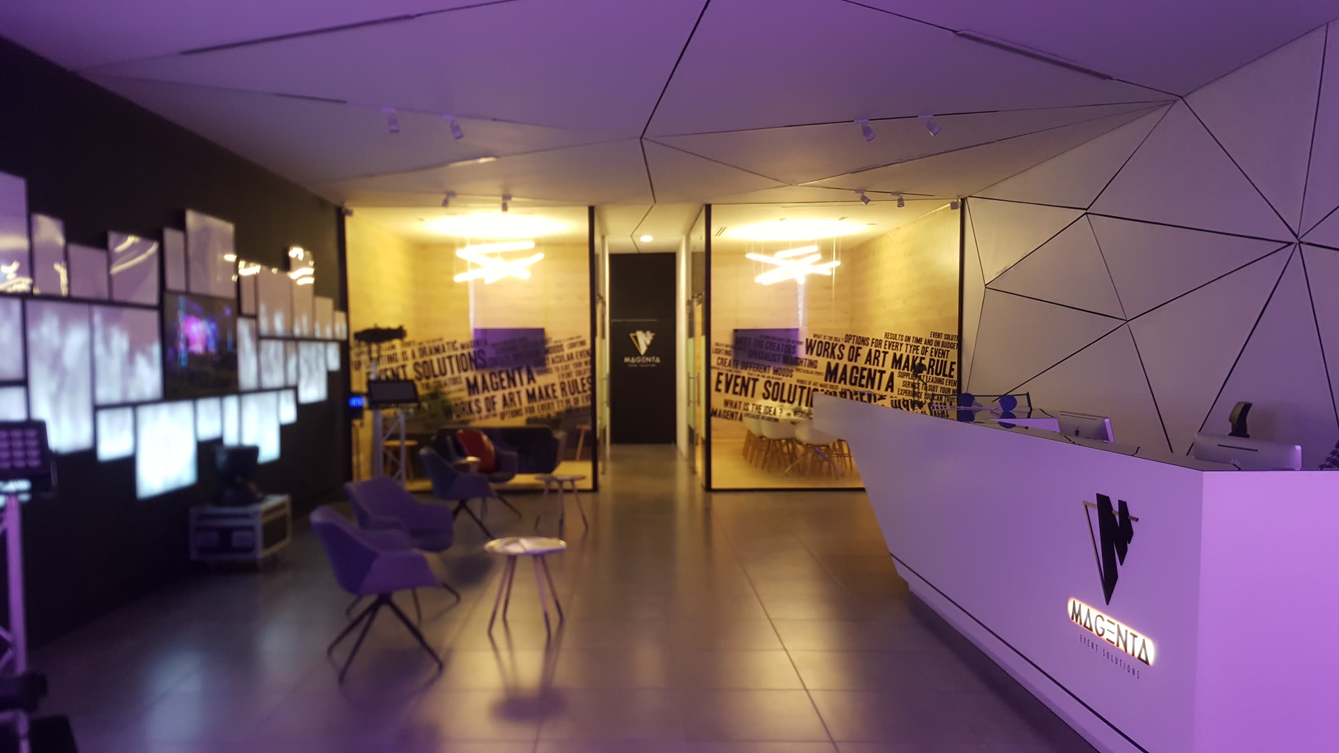 The MAGENTA reception in Jeddah: a wall of screens on the left, meeting rooms behind printed glass, and the lit Magenta mark on the reception desk.