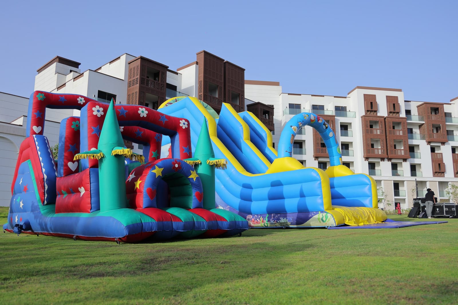 A large inflatable castle and slide set up on the lawn in front of the residences.