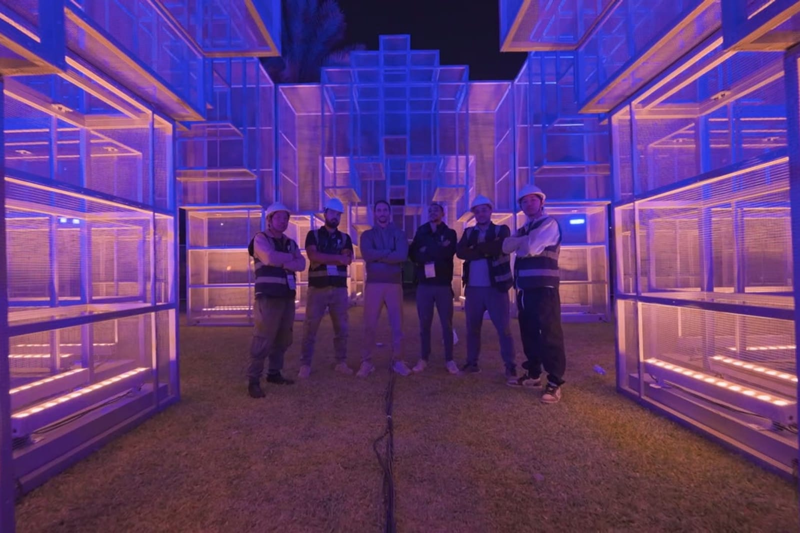 The Magenta crew standing inside the sculpture, lit blue and violet.